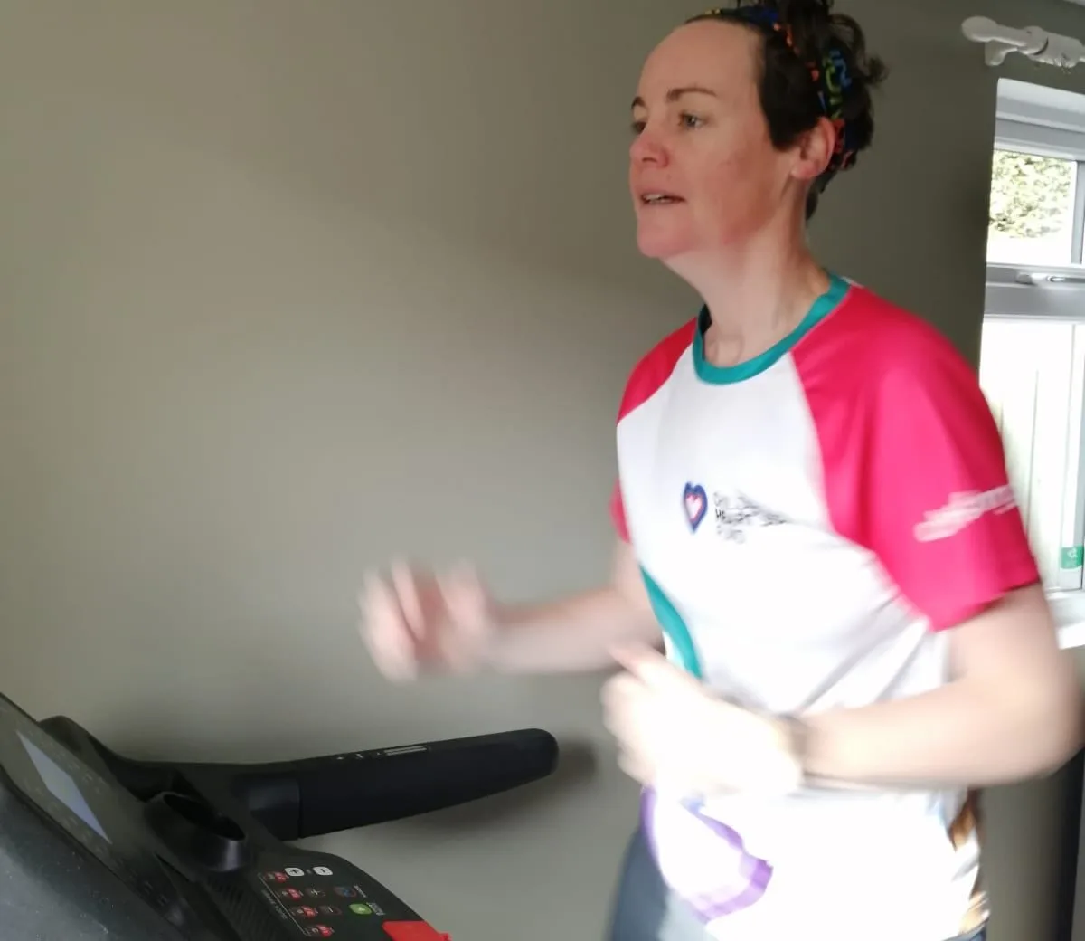 Rose's mum Katie wearing a CHSF running tshirt, running on a treadmill at home