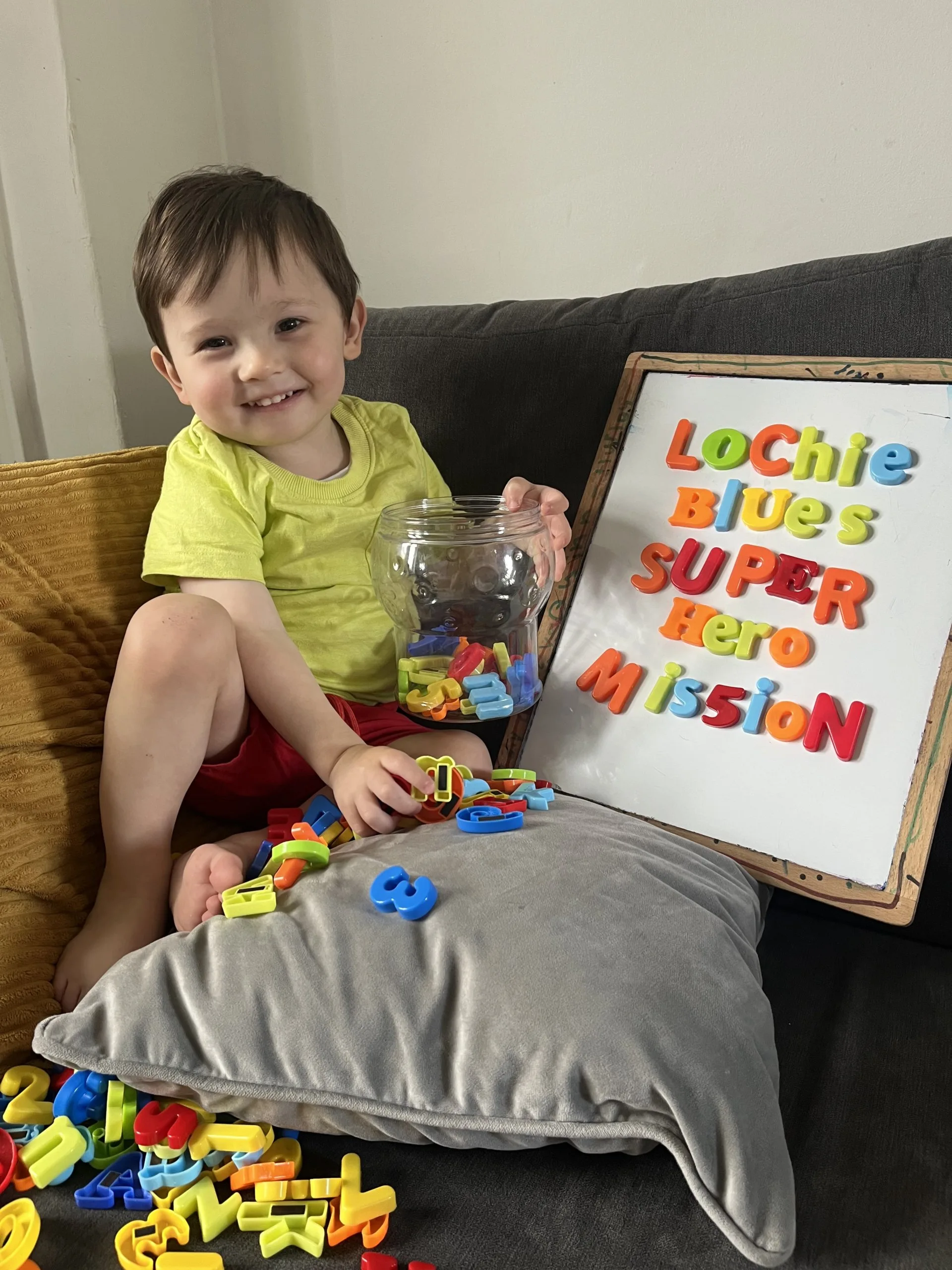 Lochie now, sat next to a sign that says 'Lochie Blue's Super Hero Mission'