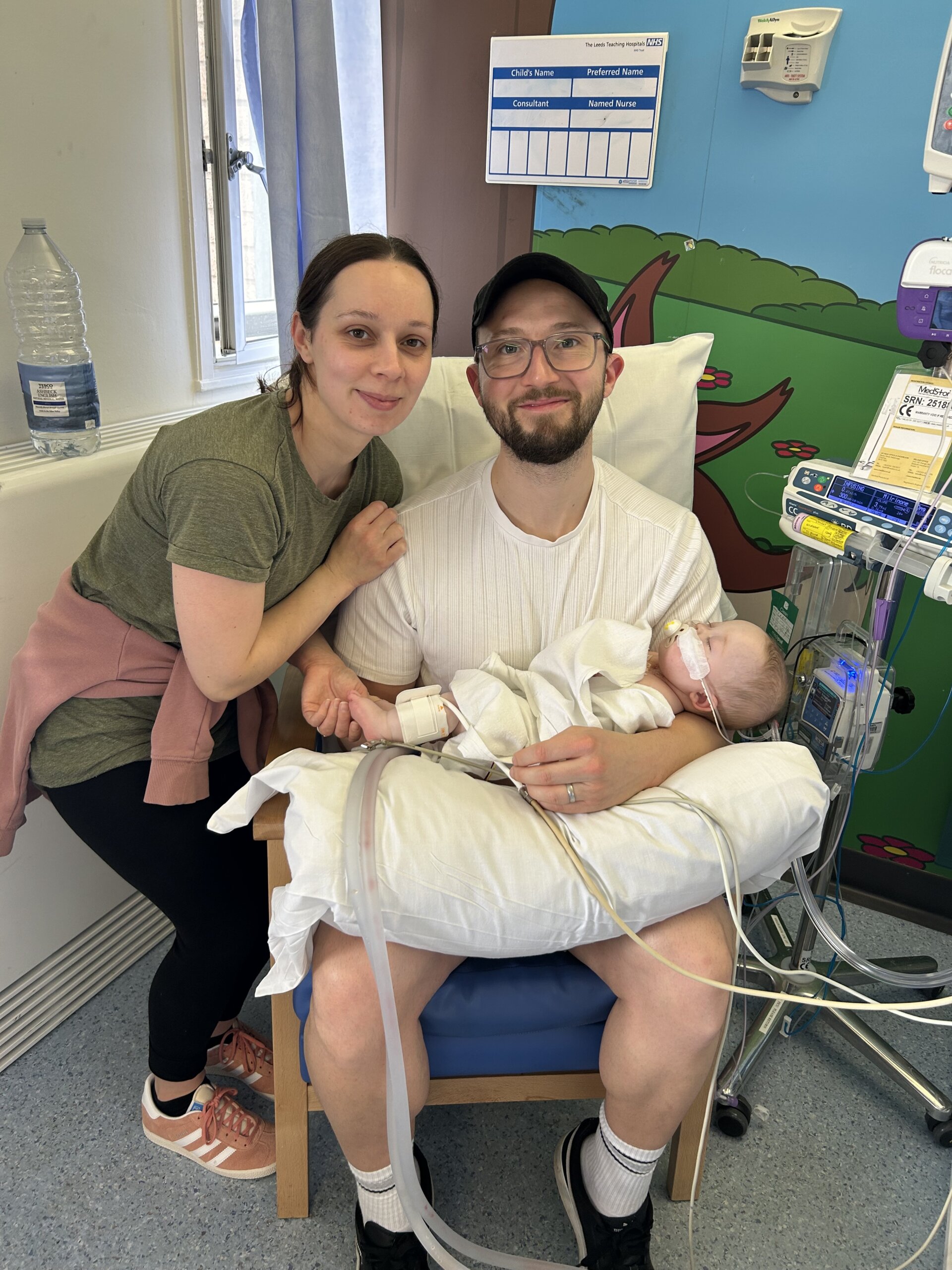 Roxy laying in a hospital bed smiling with her twin brother