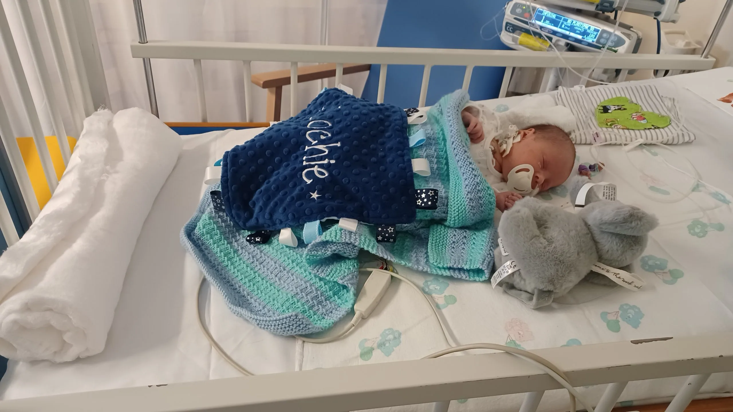 Lochie as a tiny baby in hospital in a bed with a blanket with his name on