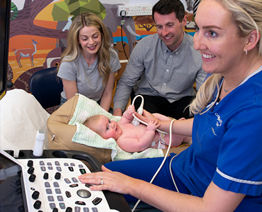 Sonographer performing an echo scan on a baby, everyone is smiling