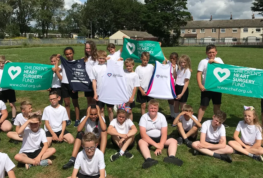 Group of school children holding CHSF banners in a field during sports day